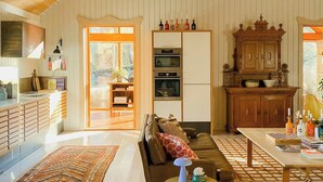 Un vaste espace de vie doté d’un haut plafond, d’une grande fenêtre, d’un canapé, d’une table basse et d’un coin cuisine à l’arrière-plan.