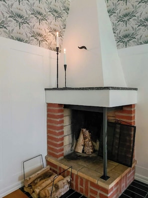A brick fireplace with a white mantel, a candle, and a decorative wall pattern.