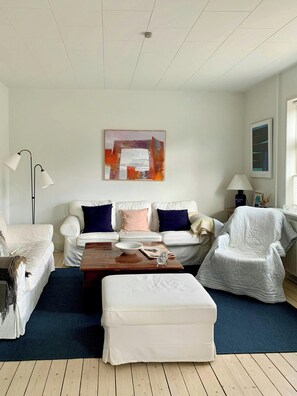 A living room with a white sofa set, a coffee table, a floor lamp, and a painting on the wall. - 1930s family holiday home in Skagen (Skagen)