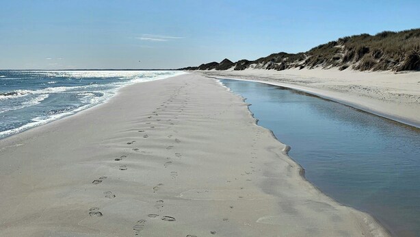 En strand med sandet bredde og en smal vandkanal.