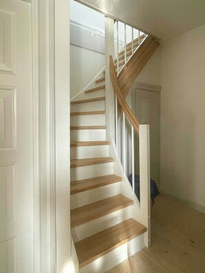Eine Treppe mit Holzbodenstufen und weißen Geländern, die zu einer oberen Etage führt.
