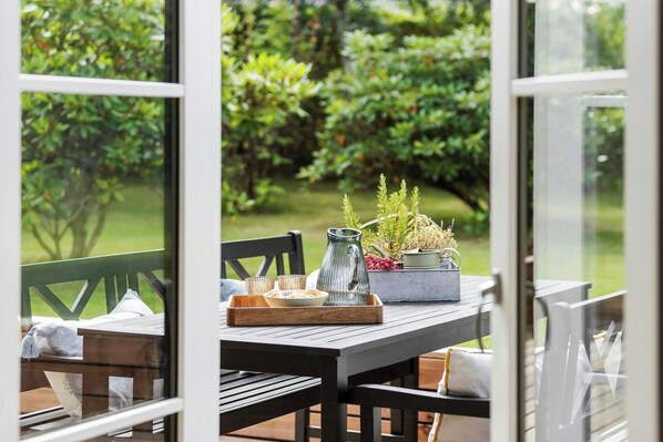 Ein Tisch gedeckt mit einer Karaffe, Gläsern und einer Tablett, mit Blick auf einen Garten.