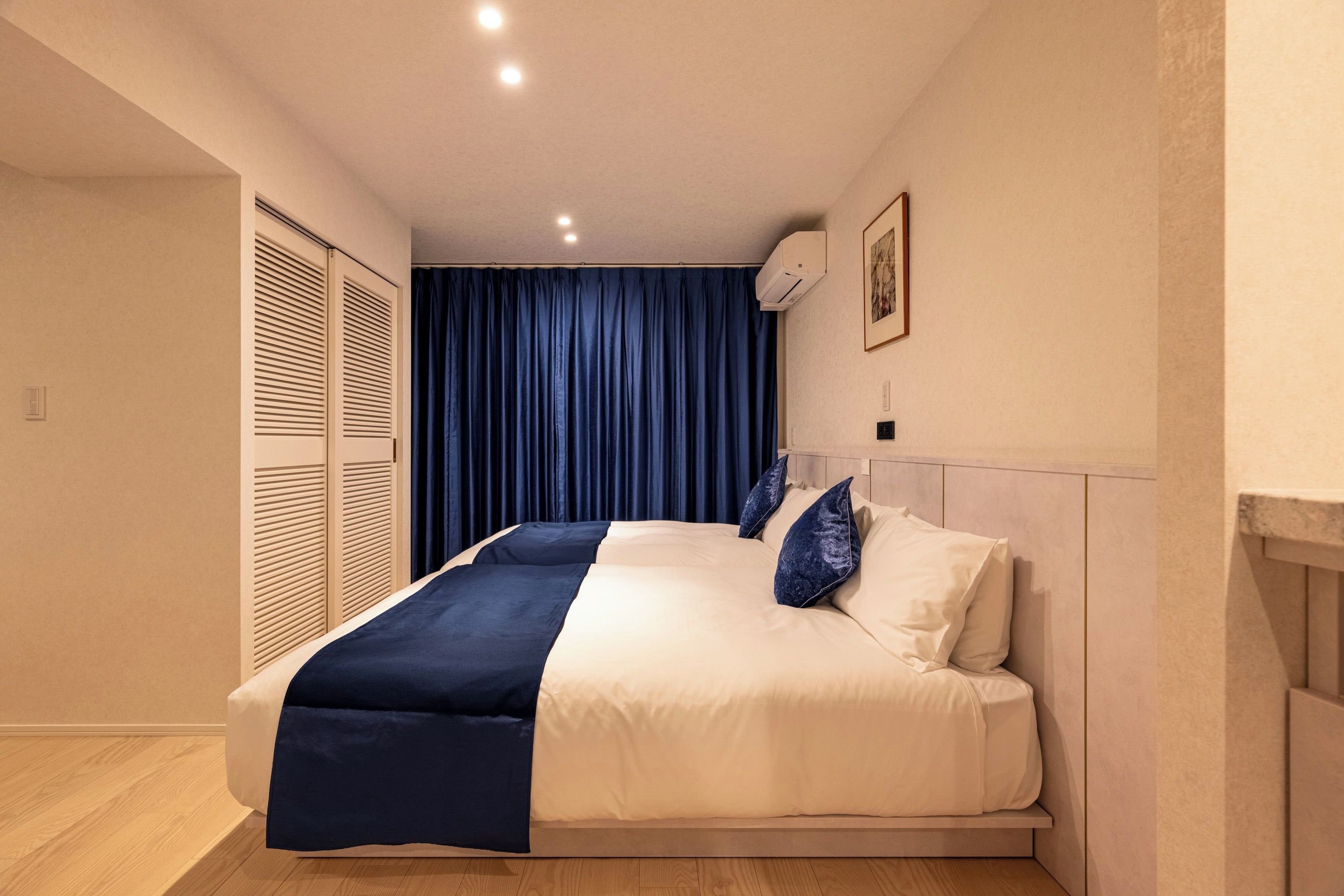 A bedroom with a bed, a wardrobe, a ceiling light, and a wall-mounted air conditioner.