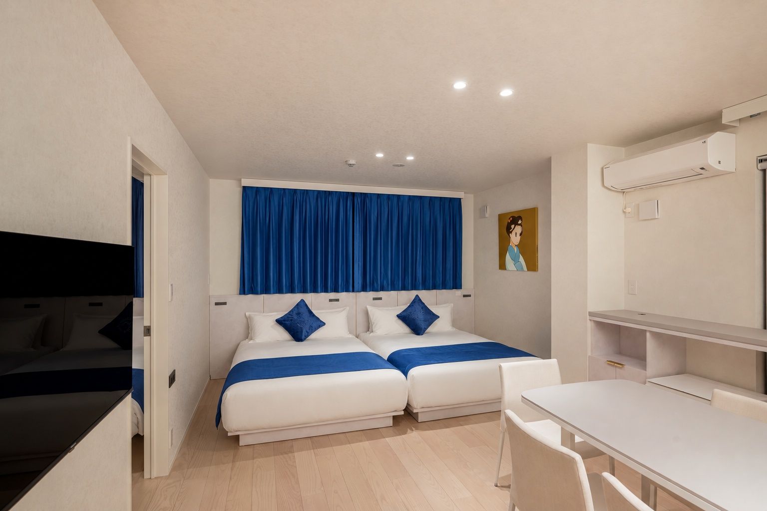 A hotel room with two beds, a desk, and a chair.