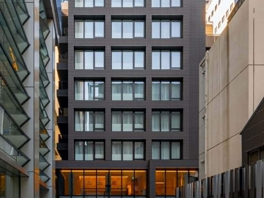 A modern building with a glass facade, multiple floors, and a central entrance with a glass door.