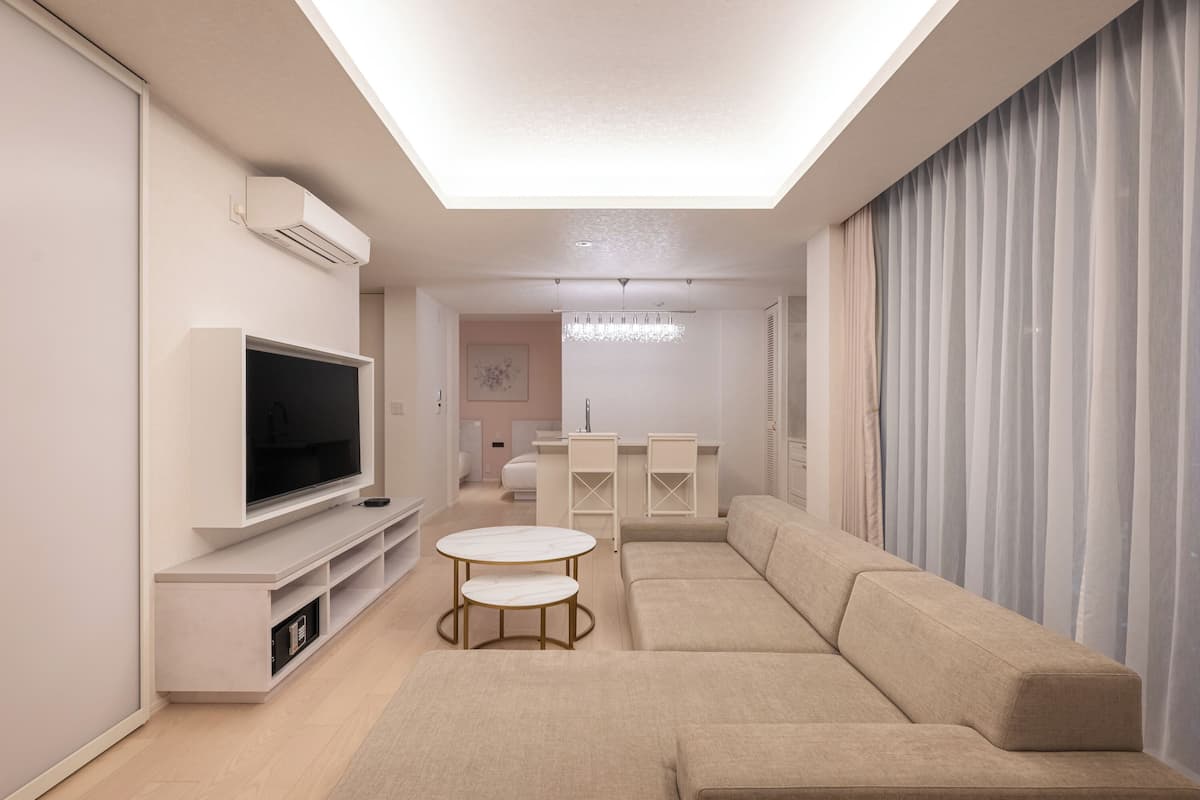 A modern living room with a flat-screen TV, a sofa, a coffee table, and a dining area.