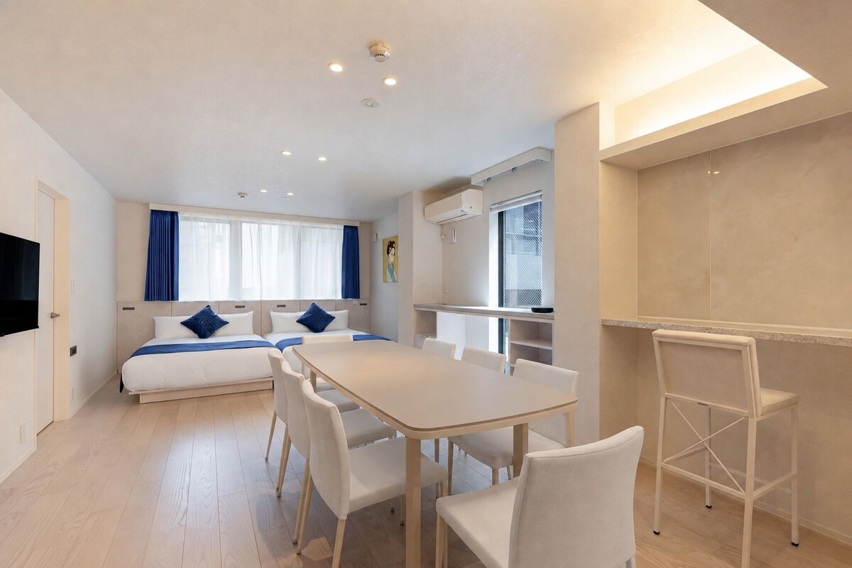 A modern hotel room with a bed, a dining table, and a TV.
