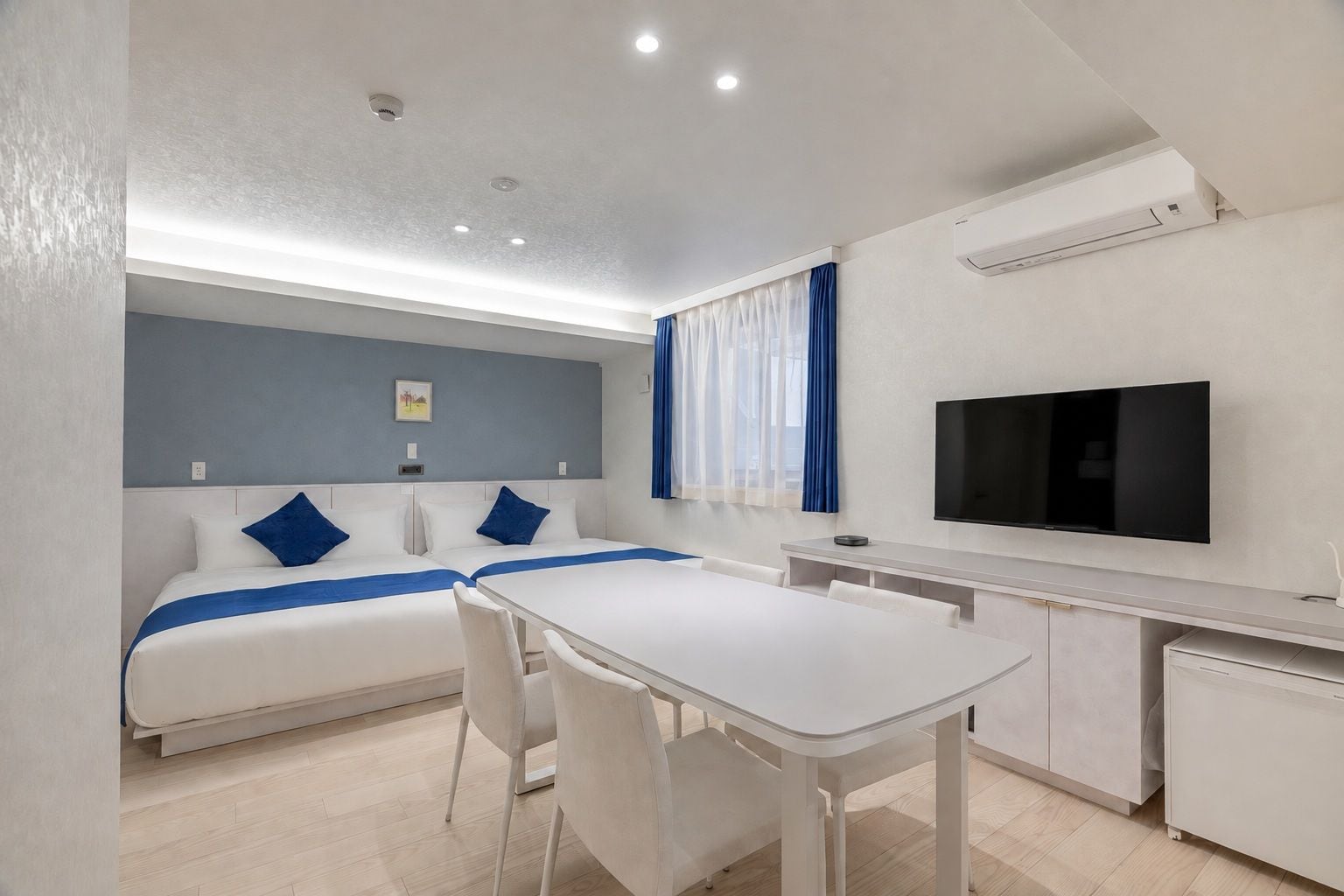 Een hotelkamer met een bed, een bureau, een stoel, een televisie en een airconditioner.