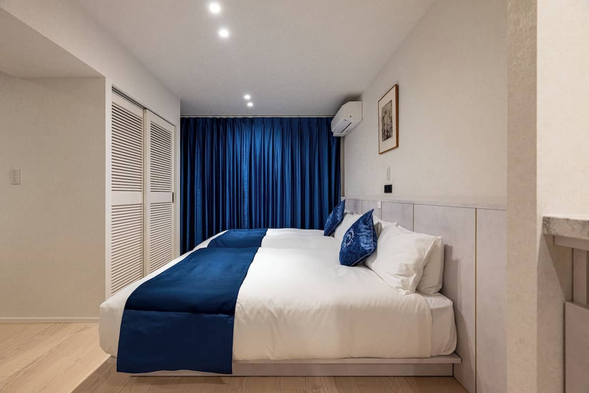 A modern bedroom with a bed, a blue curtain, and a white wall.