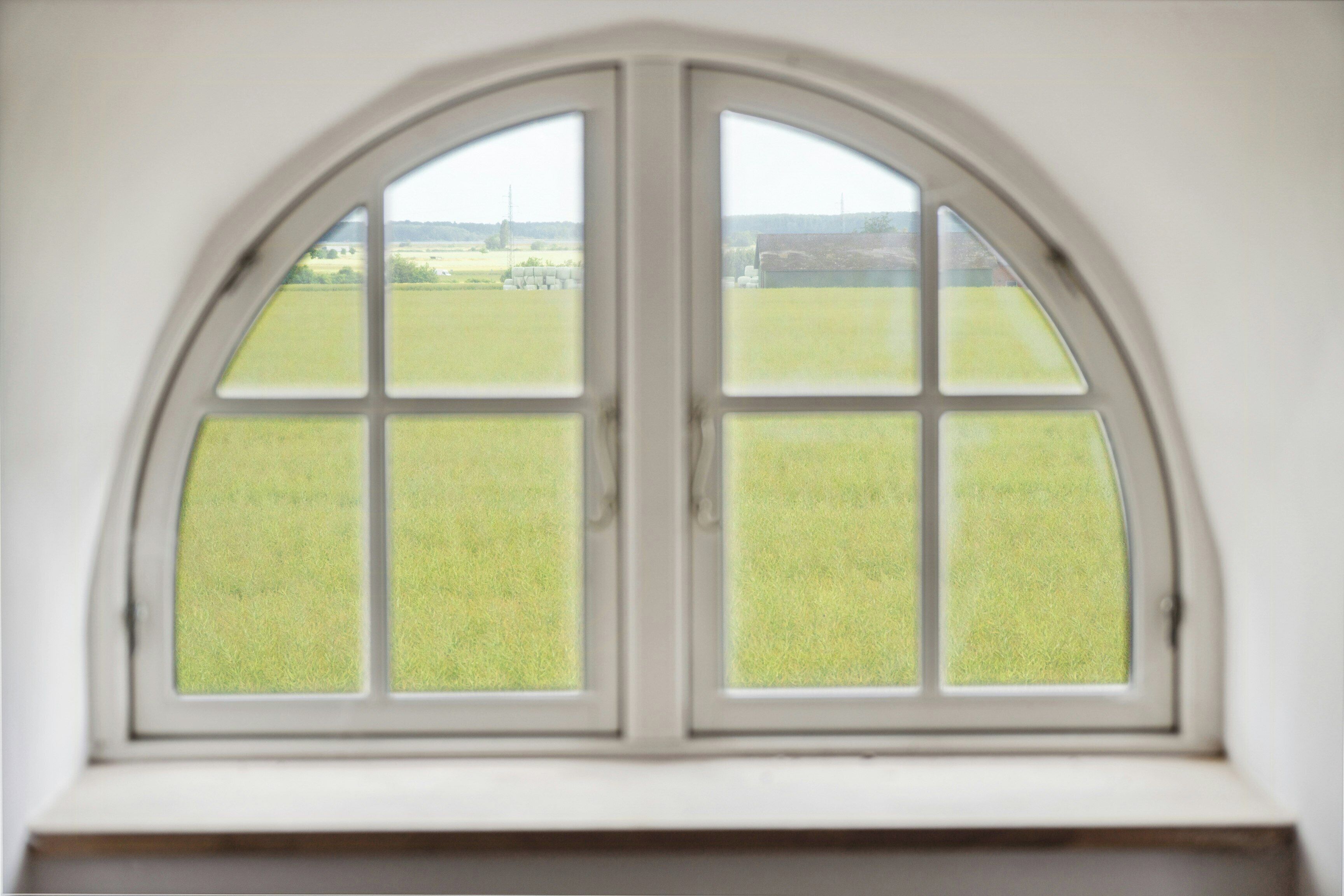 A window with a view of a green field.