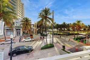 A street view with palm trees, a building with a sign 'Haagen-Dazs,' and a crosswalk. - Sunny Studio with Great Location, Smart TVs & Fully Equipped Kitchen (Miami Beach)