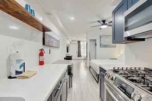 A modern kitchen with a gas stove, a ceiling fan, and a fire extinguisher. - Sunny Studio with Great Location, Smart TVs & Fully Equipped Kitchen (Miami Beach)