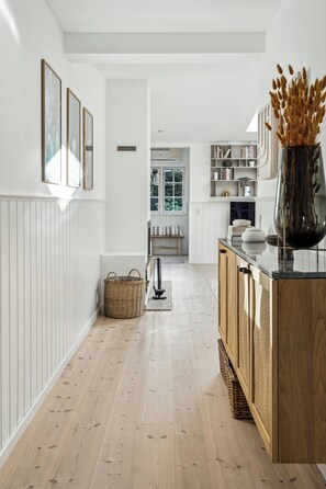 A modern kitchen with wooden cabinets, a central island, and a view into the dining area.