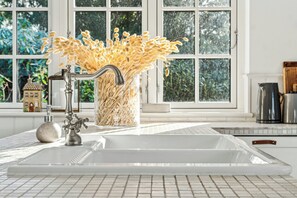 A kitchen with a sink, faucet, and a vase with dried flowers.