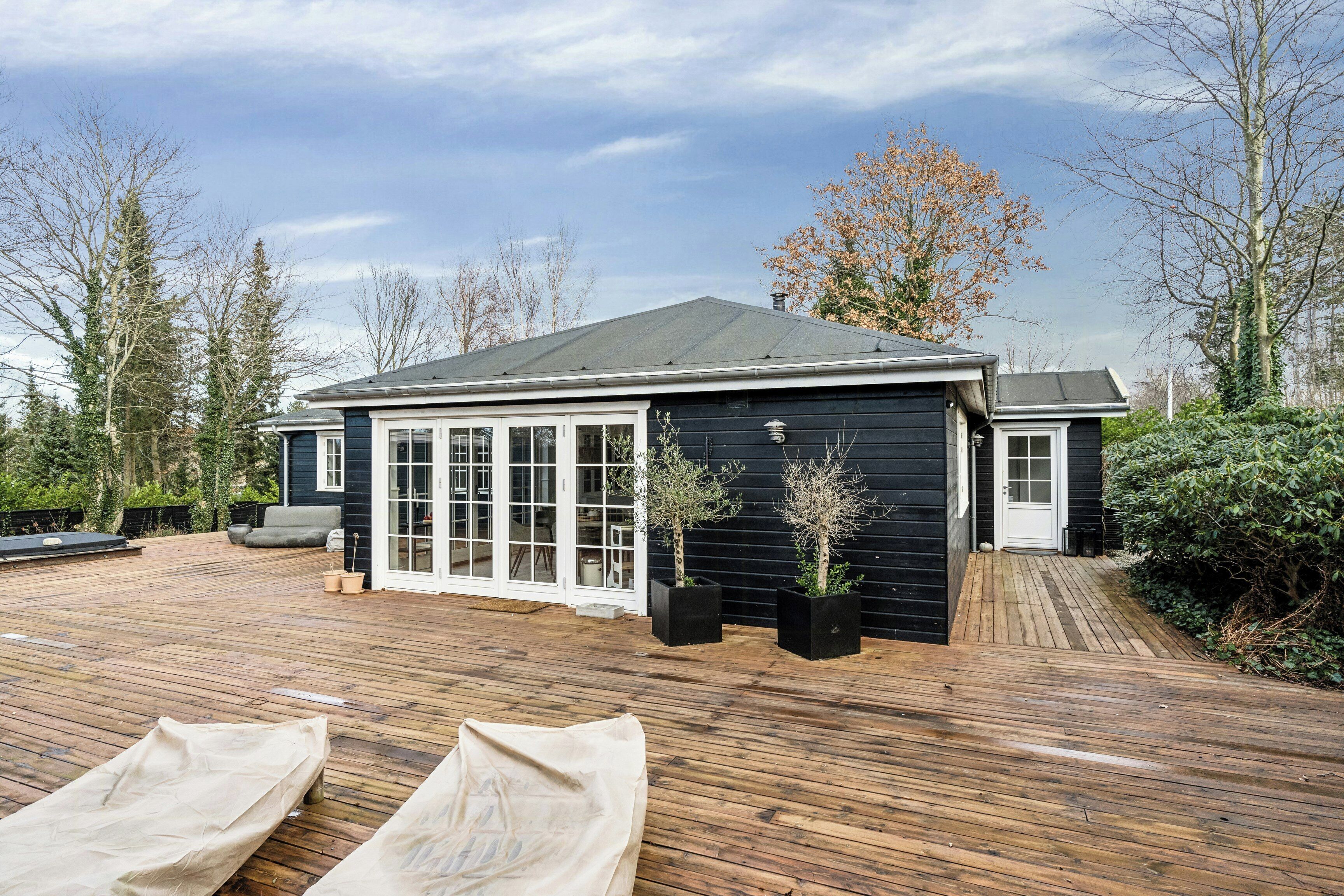 A house with a wooden deck, a covered patio, and a garage.