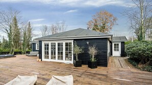 Une maison avec une terrasse en bois, un patio couvert et un garage.