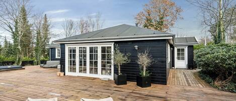 A house with a wooden deck, a covered patio, and a garage.
