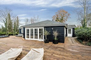 A house with a wooden deck, a covered patio, and a garage.