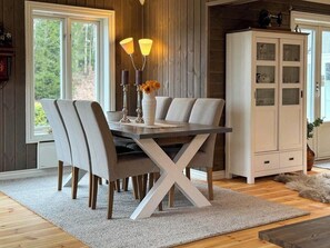 A dining area with a table and chairs, a cabinet, and a window with a view of trees. - Modern cabin near family beaches in Holmsbu (Holmsbu)