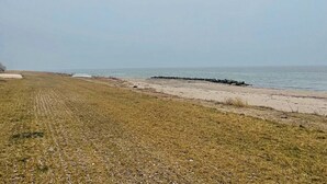 A beach with a grassy area and a rocky shoreline. - Colorful character and charm by Nakskov Fjord (Nakskov)