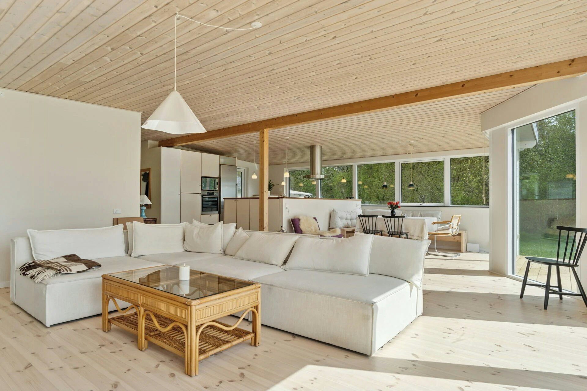 A modern living room with a sectional sofa, a glass-top coffee table, and a dining area with a table and chairs.