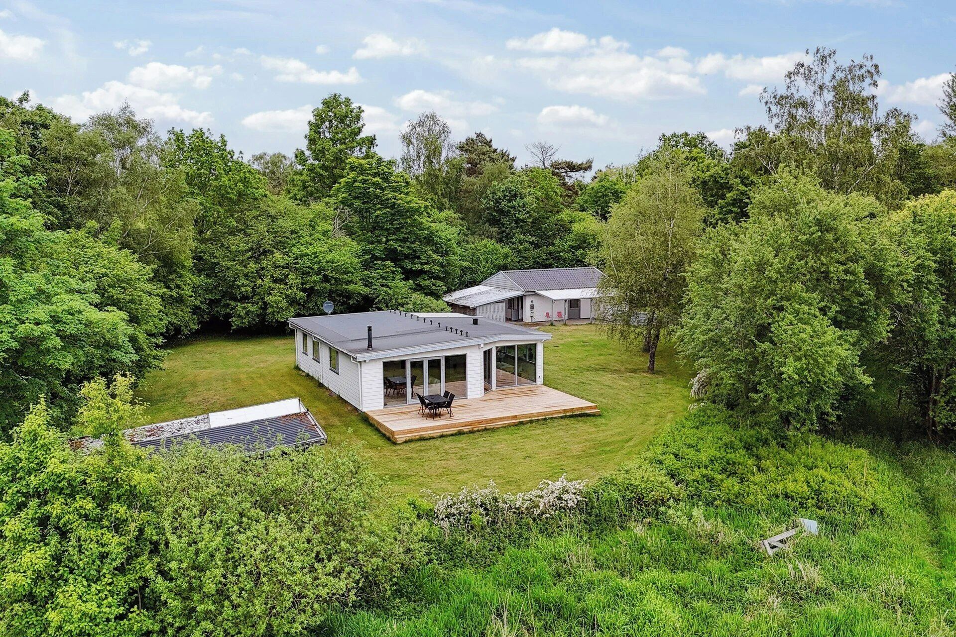 Une maison moderne dotée d’une terrasse, entourée d’une végétation luxuriante.