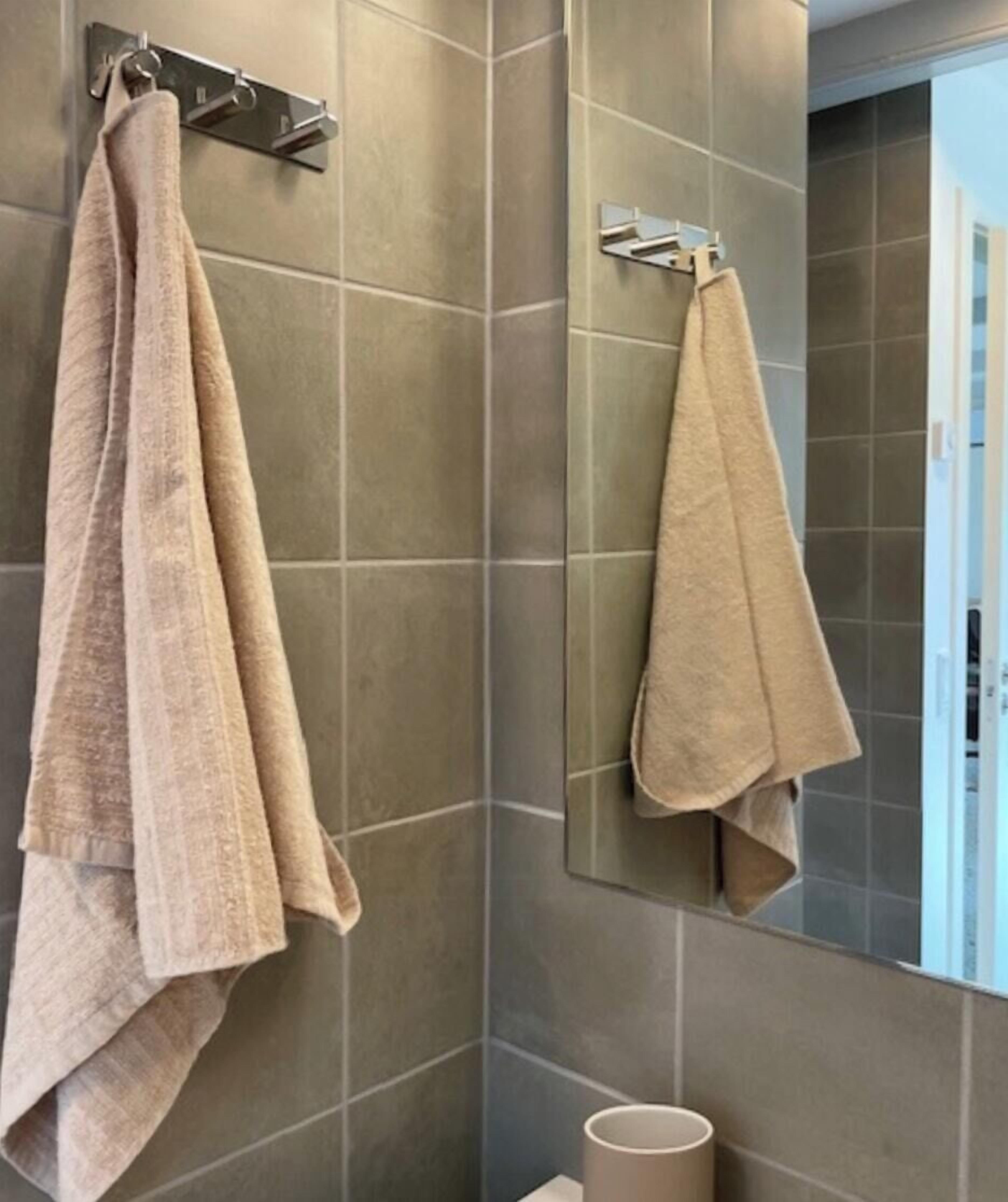 Une salle de bain avec deux serviettes suspendues à des porte-serviettes, un miroir et des toilettes.