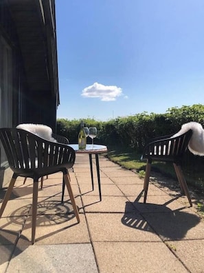 An outdoor patio with two chairs, a table, and a bottle of wine. - Holiday home with sea views over the Western Sea (Vestervig)