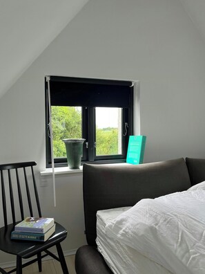 A room with a bed, a chair, a window, and a view of greenery outside. - Holiday home with view of Dalby Bay (Mesinge)