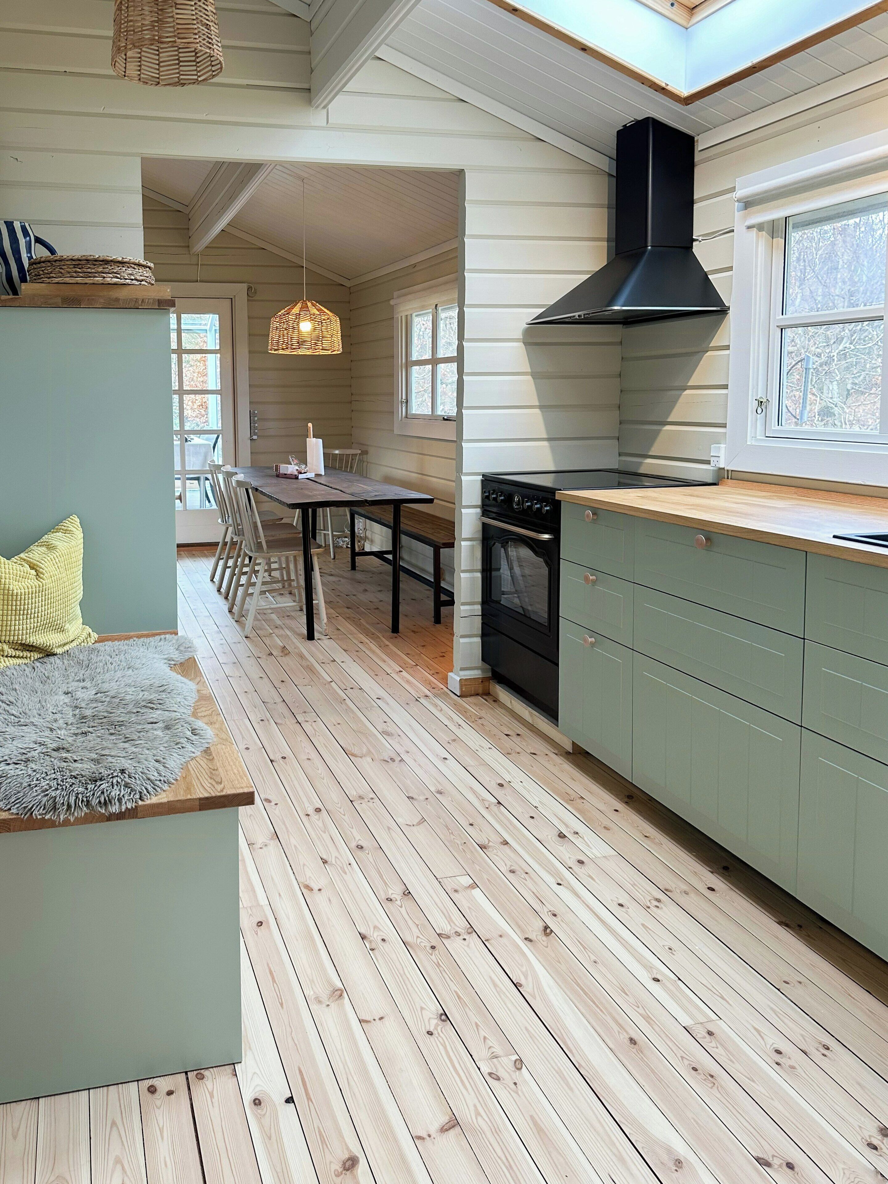 A kitchen with wooden flooring, a dining area with a table and chairs, and a window with a view.
