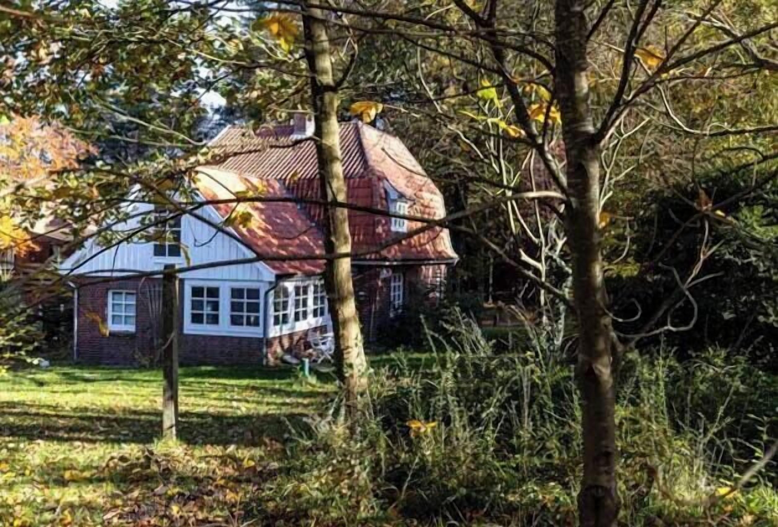 Une maison traditionnelle avec un toit rouge, des murs blancs et une porte d’entrée bien visible.