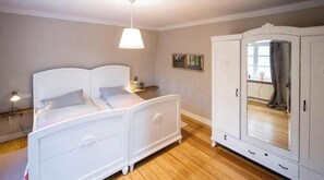 Un dormitorio con cama, mesita de noche, lámpara, armario y ventana.