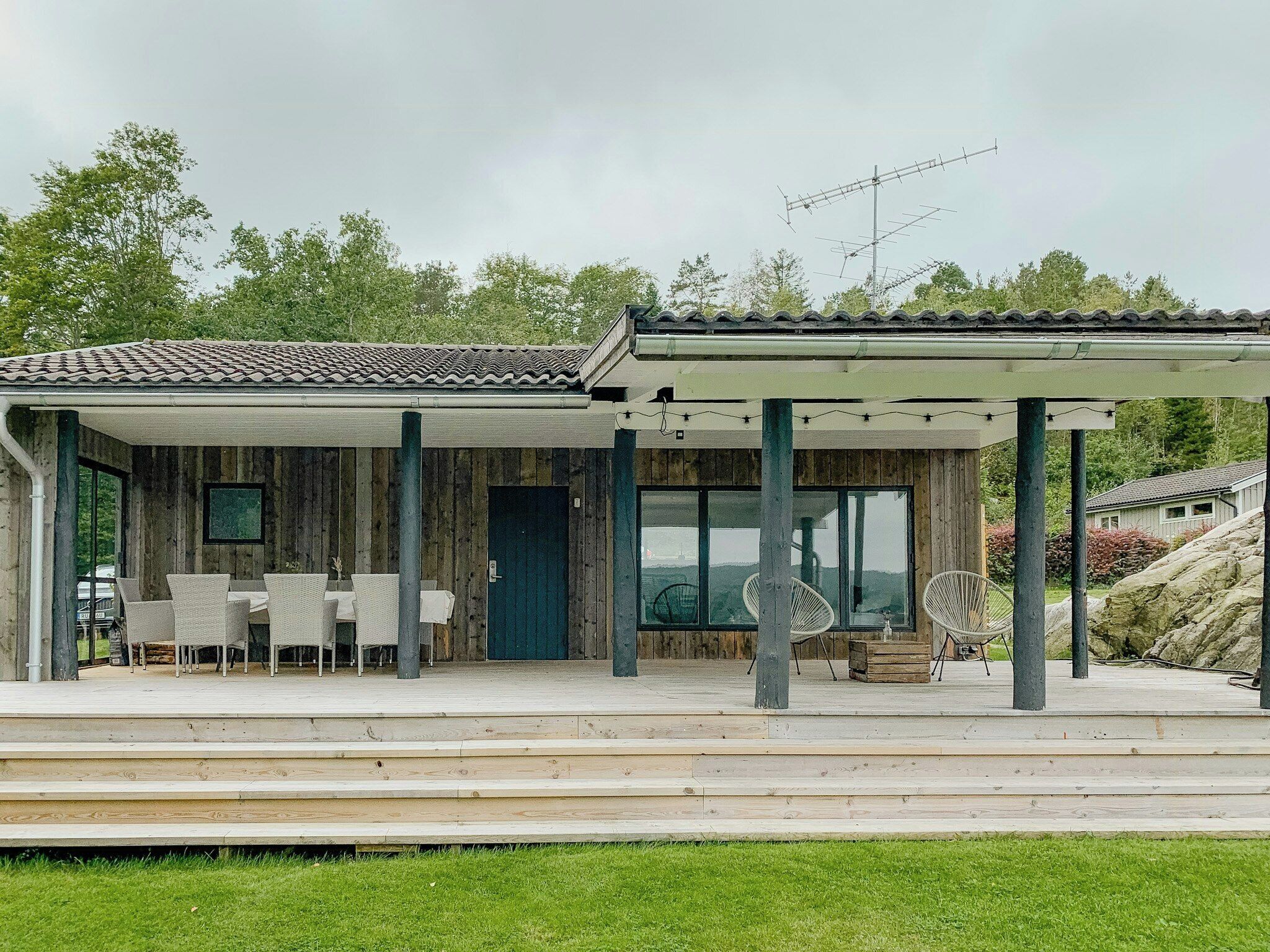 Una casa de madera con un porche cubierto, mobiliario exterior y vistas del paisaje circundante.