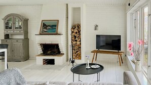 Uma sala de estar com lareira, televisão, sofá e mesa de jantar.