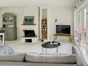 A living room with a fireplace, a television, a sofa, and a dining table. - Cozy cabin with fjord view and fireplace (Uddevalla)
