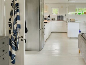 A modern kitchen with white cabinets, a stainless steel refrigerator, and a window with a view of greenery. - Cozy cabin with fjord view and fireplace (Uddevalla)