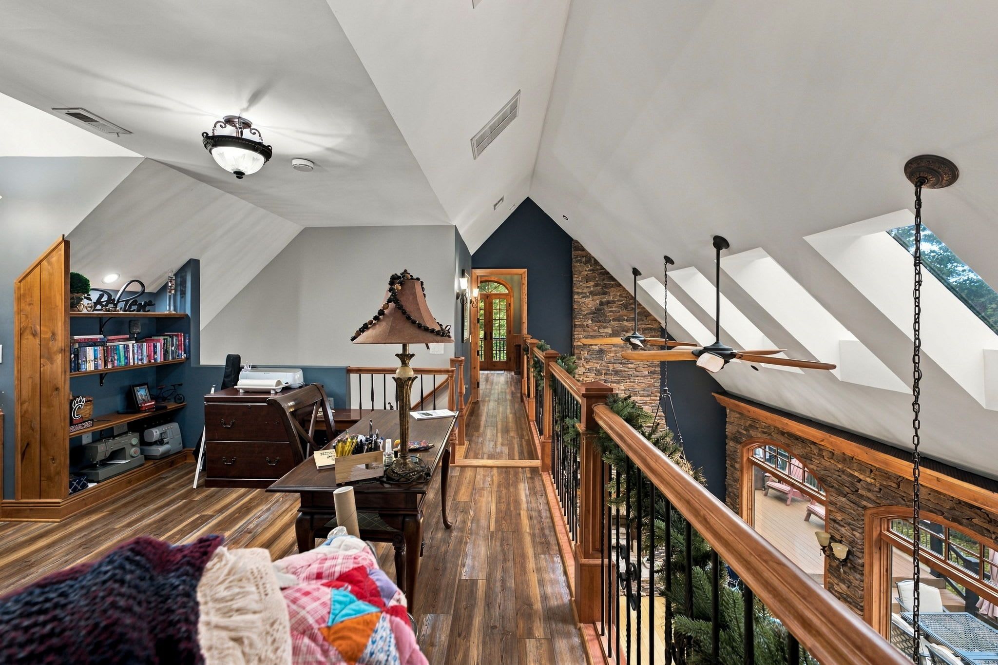 A spacious loft with a high ceiling, wooden flooring, a central staircase, and a view of the outdoors.
