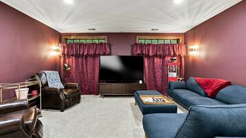 A living room with a flat-screen TV, leather armchairs, a sofa, and a coffee table.