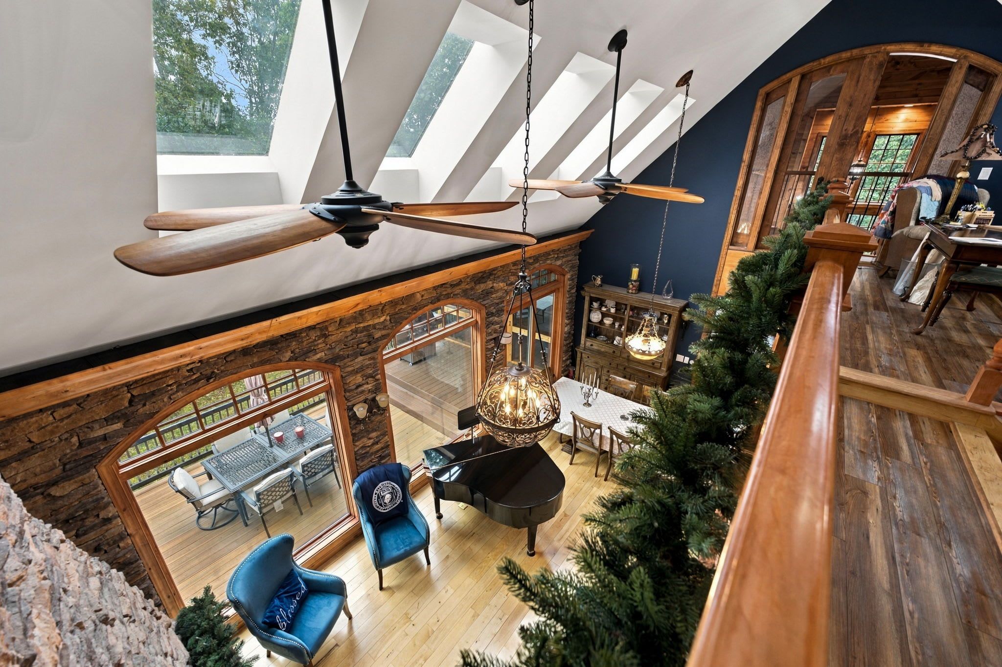 A spacious loft with a high ceiling, exposed wooden beams, a piano, and a dining area with a view of the outdoors.