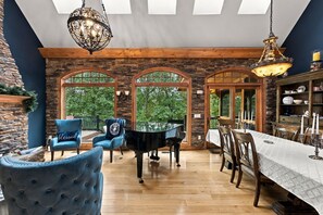 A dining area with a piano, blue chairs, and a table set for a meal.