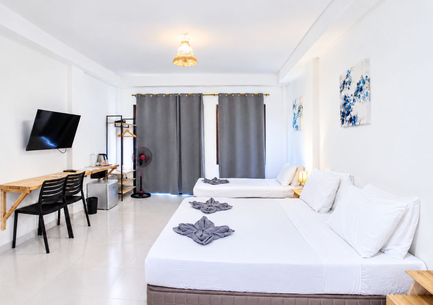 Une chambre d’hôtel équipée d’un lit, d’un bureau avec un ordinateur, d’une télévision et d’un ventilateur.