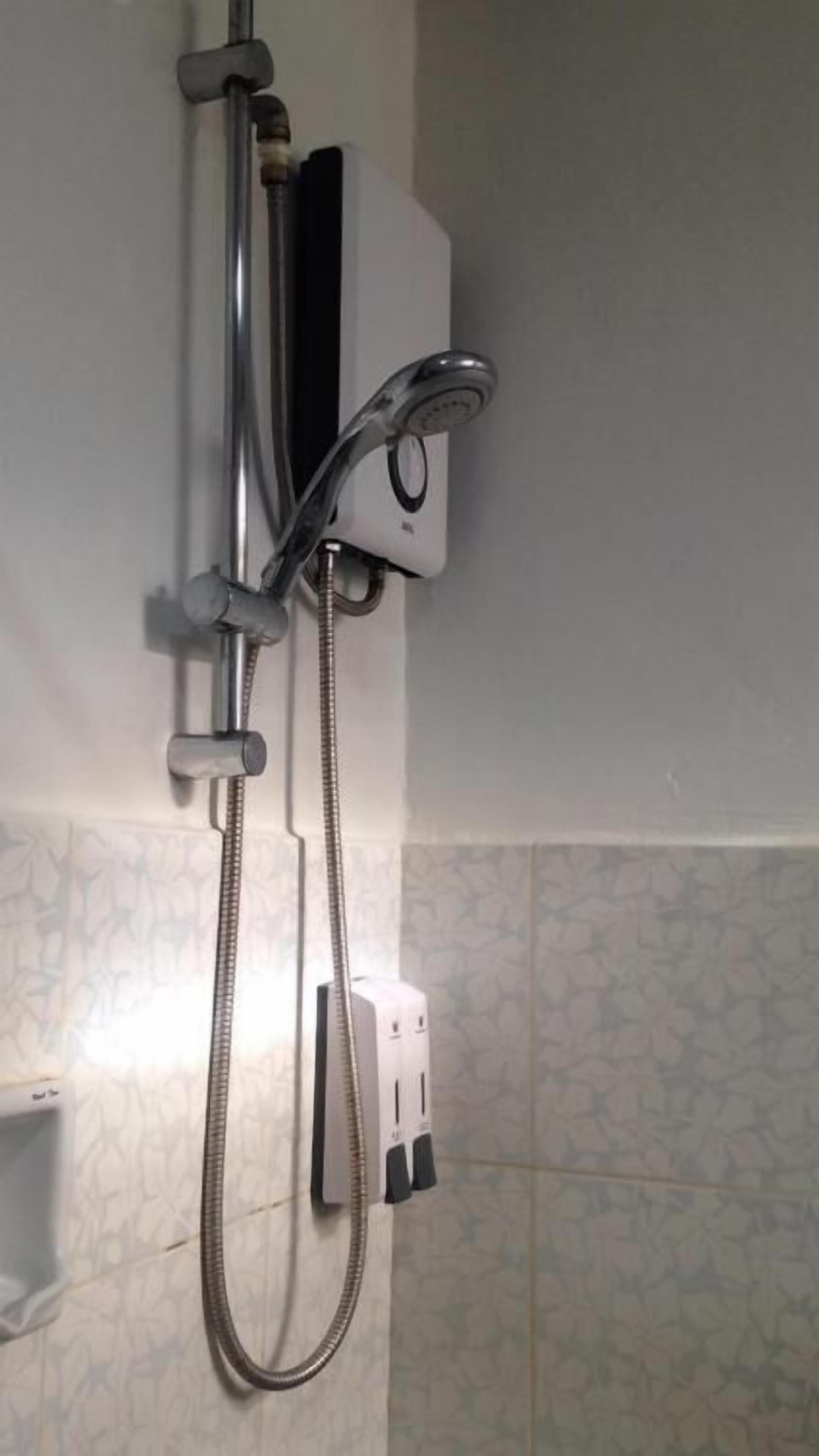 A shower with a handheld showerhead and a wall-mounted control panel.