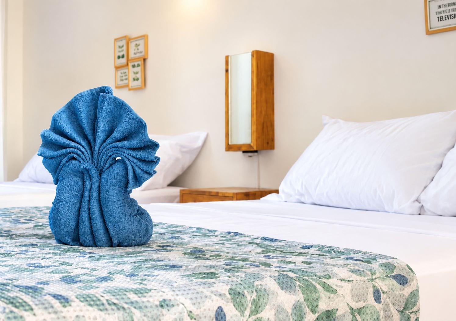 A hotel room with a neatly made bed, a blue bathrobe on the bed, and a wall-mounted nightstand with a lamp.