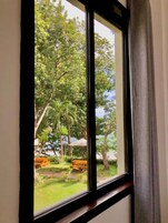A window with a view of a garden area, including trees and outdoor furniture.