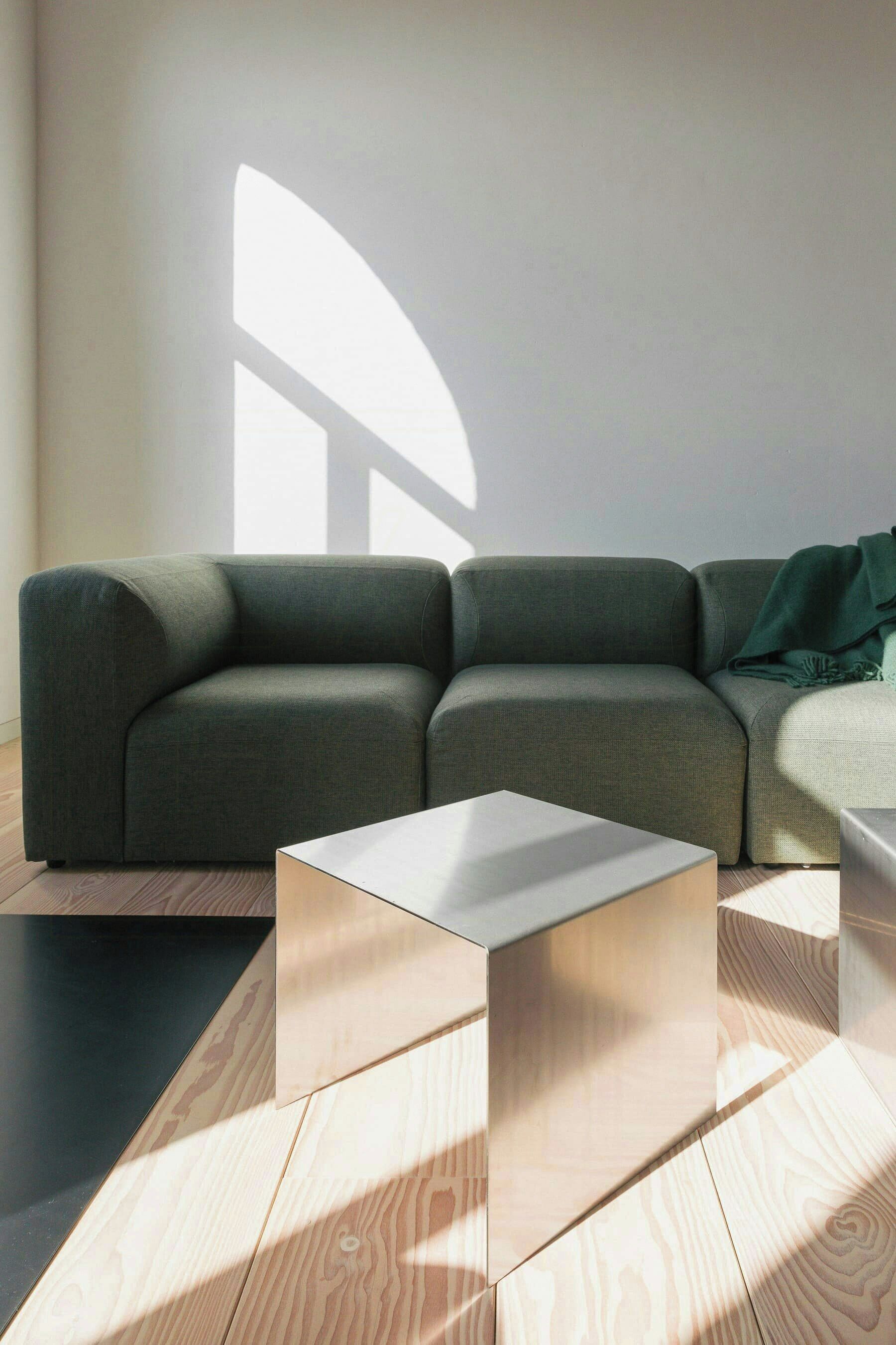 Ein modernes Wohnzimmer mit einem Ecksofa, einem schlichten Couchtisch und einem Boden mit geometrischem Muster.