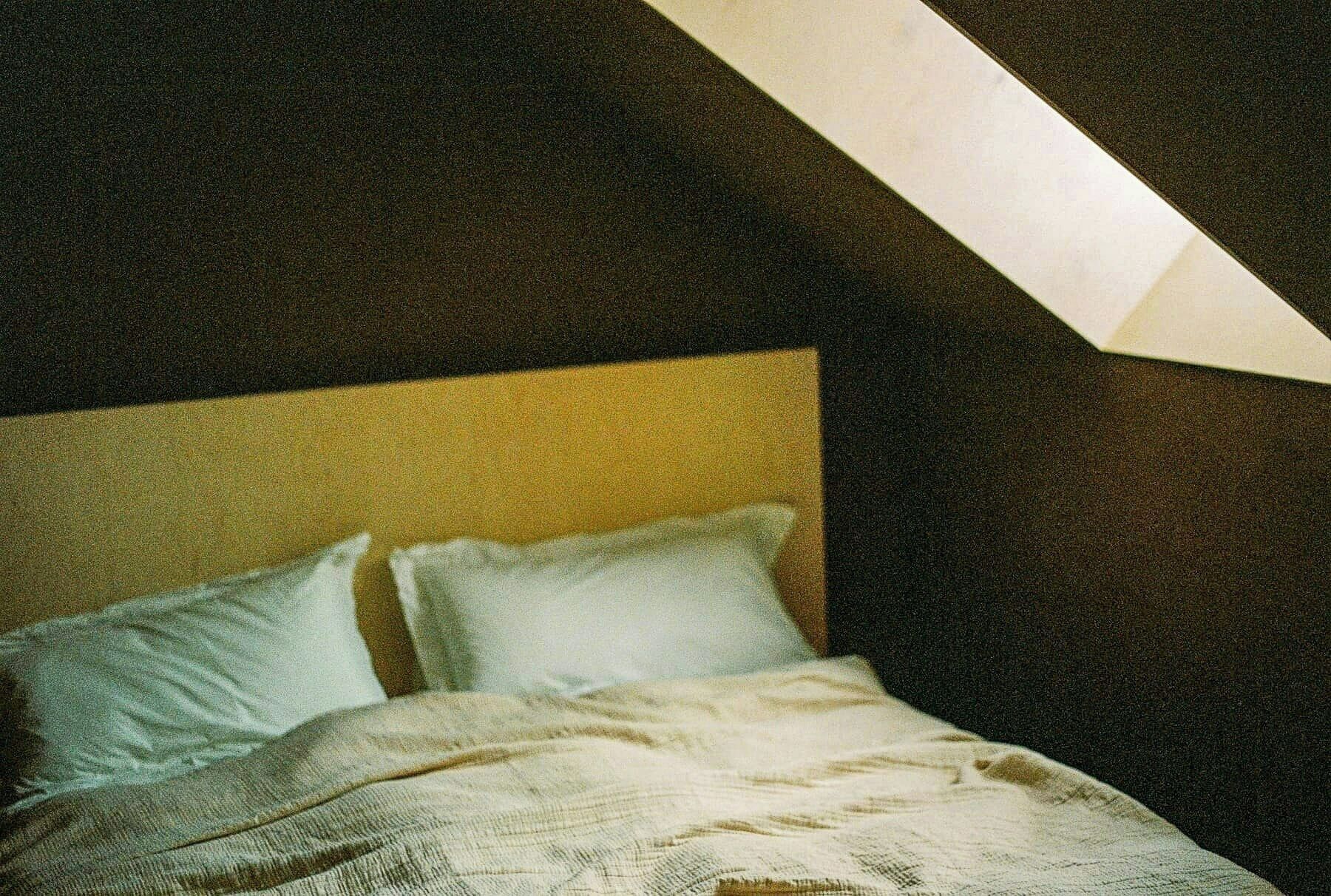 A bedroom with a bed, pillows, and a slanted ceiling.