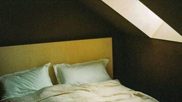 A bedroom with a bed, pillows, and a slanted ceiling.