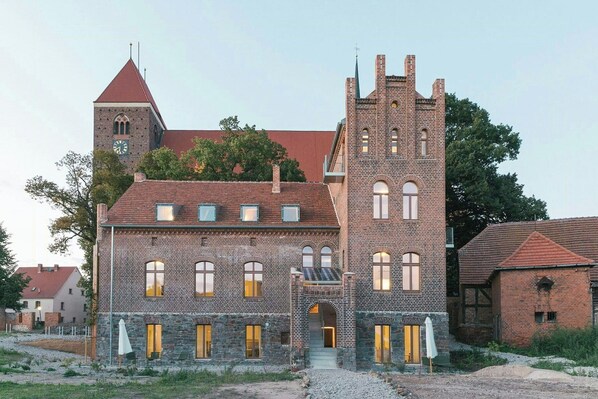 A historic building with a prominent tower, arched windows, and a stone facade. - Attic flat with balcony and sauna in Naulitz (Werben)