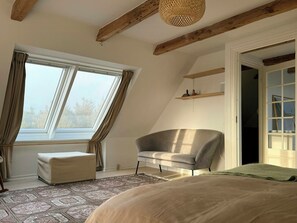 A room with a large window, a sofa, a chair, and a bed. - House with soul in Klitmøller (Klitmøller)