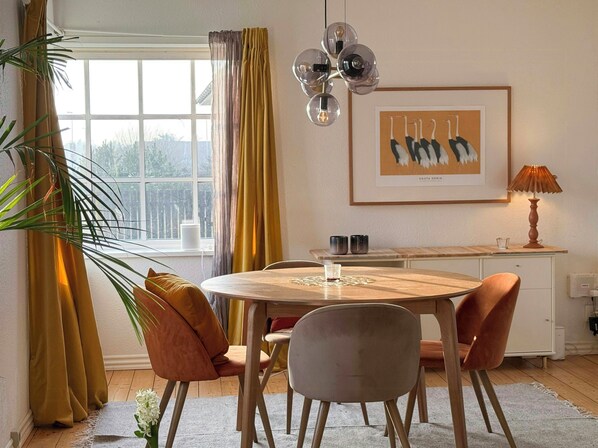 A dining area with a round table, chairs, a pendant light, a framed artwork, and a lamp. - House with soul in Klitmøller (Klitmøller)